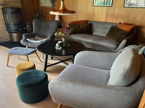 Ein gemütliches Wohnzimmer mit einem grauen Sofa, einem runden Couchtisch und einem kleinen Hocker.