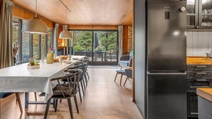 A modern kitchen with a black refrigerator, wooden ceiling, and large windows. - "Sheyla" - 70m from the sea by Interhome (Væggerløse)