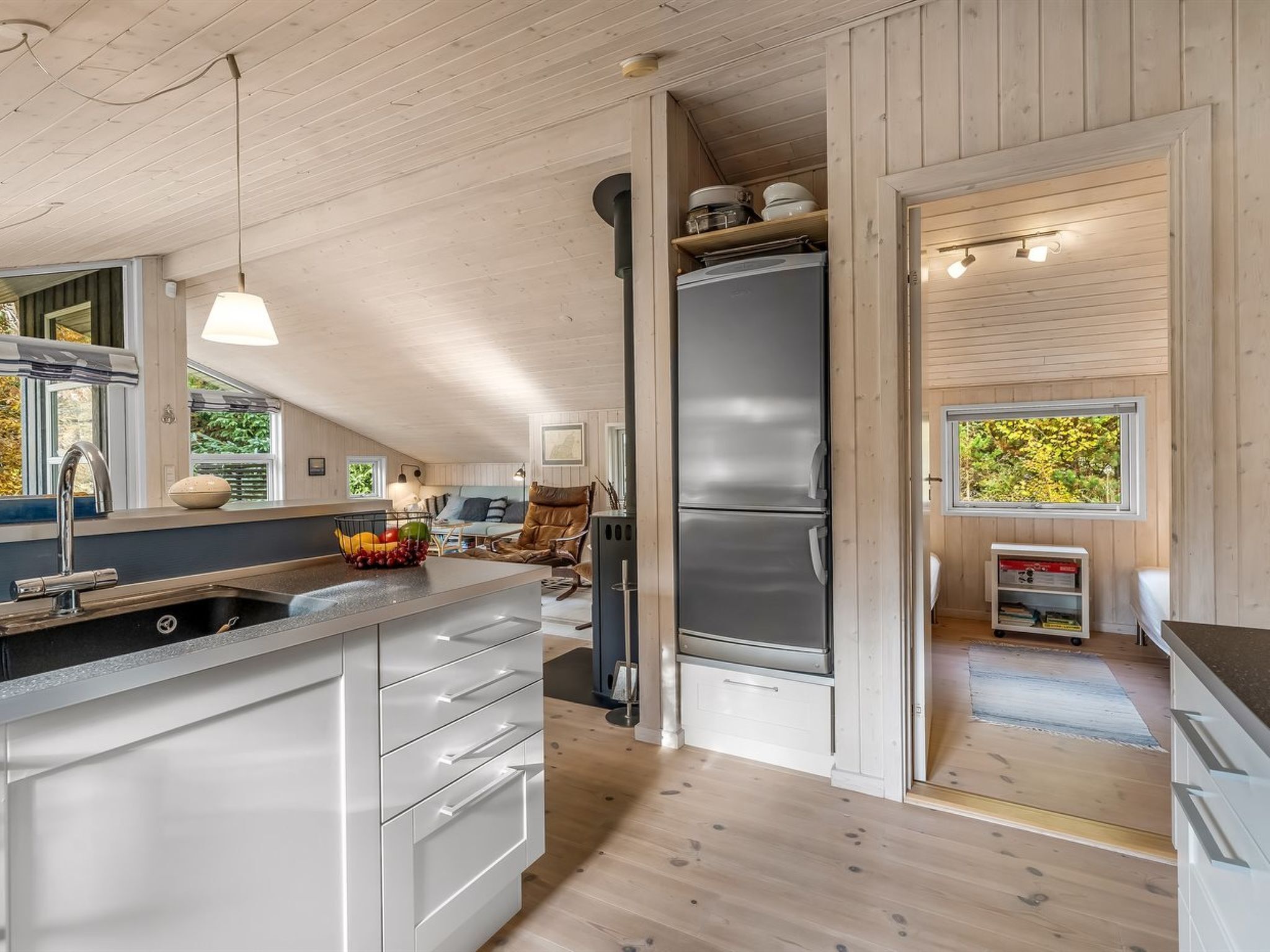 Une cuisine moderne dotée d’un réfrigérateur encastré, de meubles en bois et d’une grande fenêtre qui laisse entrer la lumière naturelle.