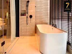 Un baño moderno con una bañera independiente, cabina de ducha de vidrio y tocador con artículos de aseo.