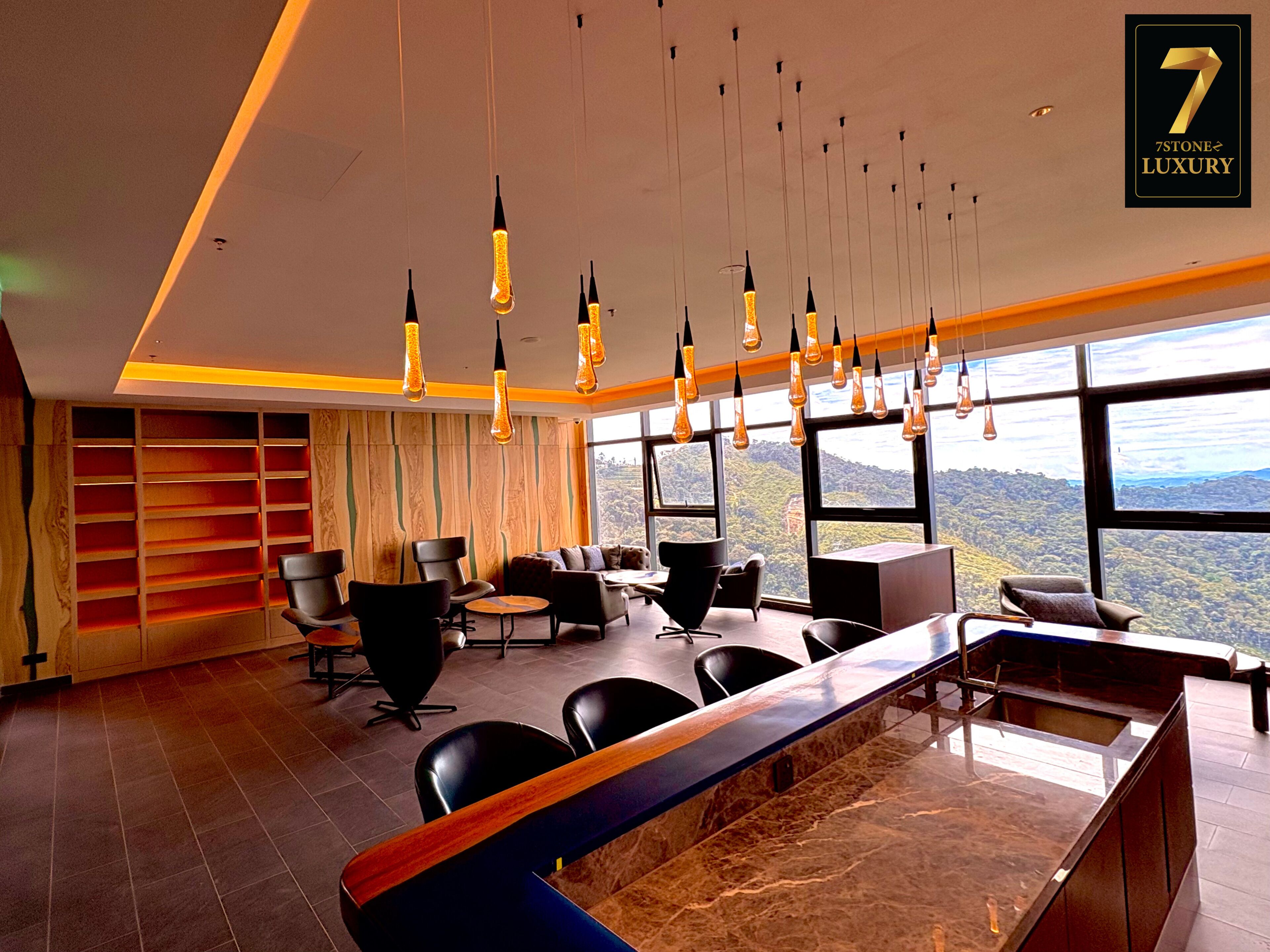 A modern hotel lobby with a marble reception desk, black leather chairs, and a large window offering a scenic view.