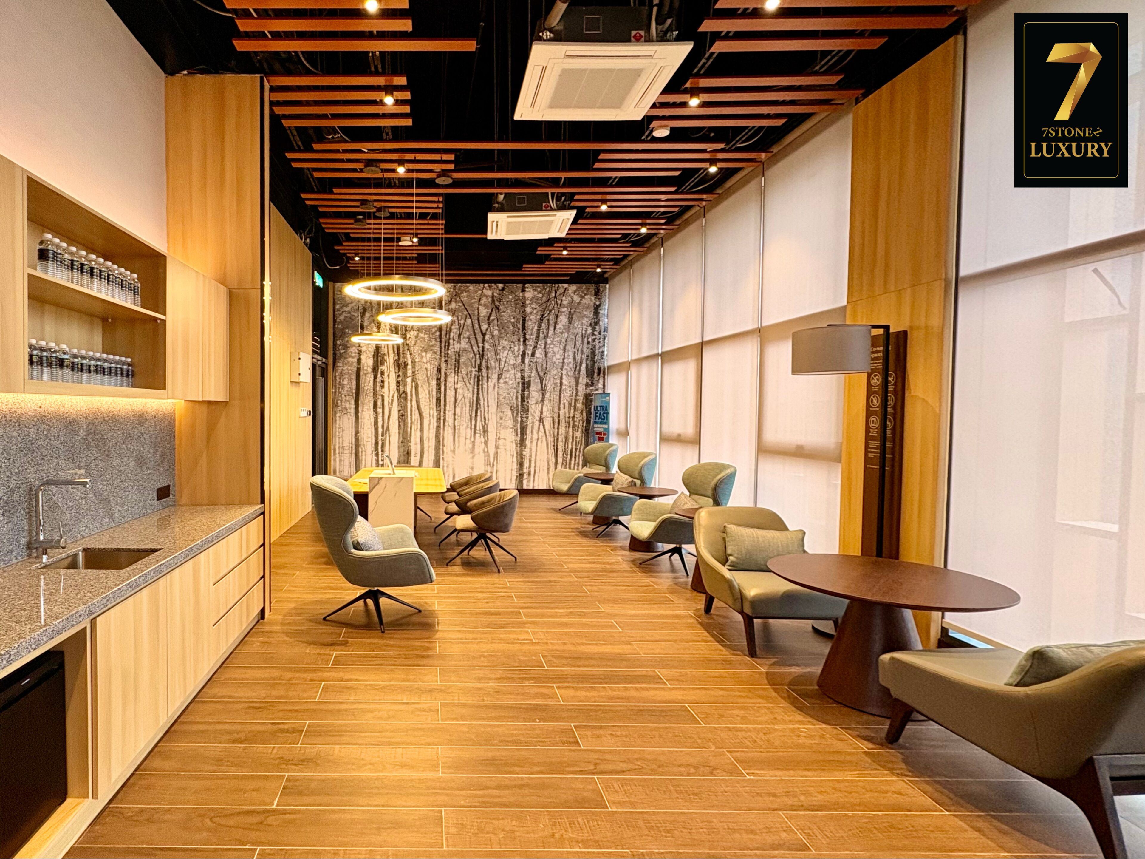 Un intérieur moderne avec un plancher en bois, un coin cuisine et un espace salon comprenant plusieurs chaises et une table ronde.