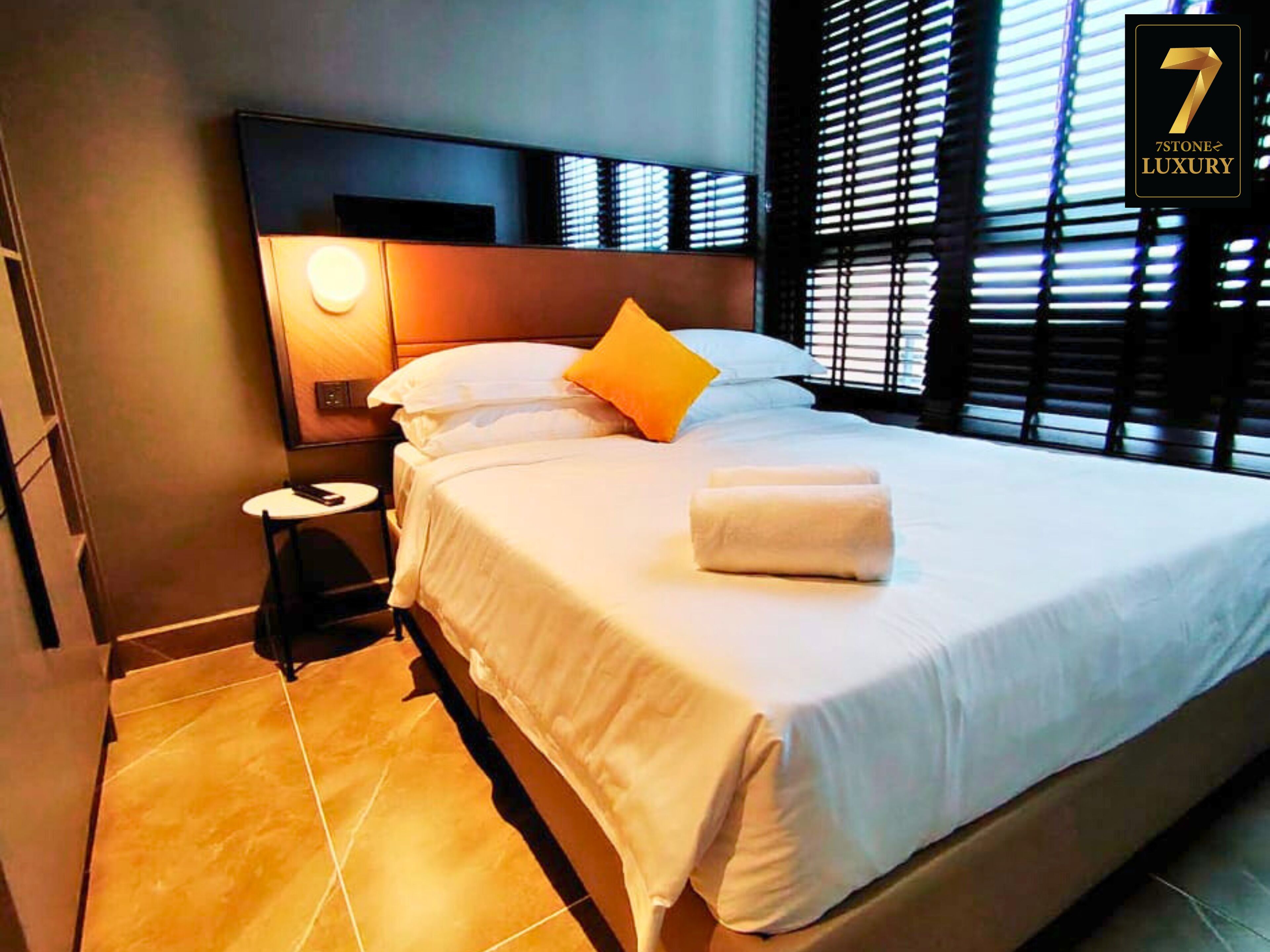 A hotel room with a large bed, a bedside table, and a nightstand.