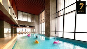 Une piscine intérieure à l’eau claire, dotée de grandes fenêtres et d’un panneau indiquant qu’il s’agit d’un hôtel de luxe.
