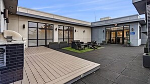 Un edificio moderno con un patio que cuenta con asientos al aire libre y una parrilla de barbacoa.
