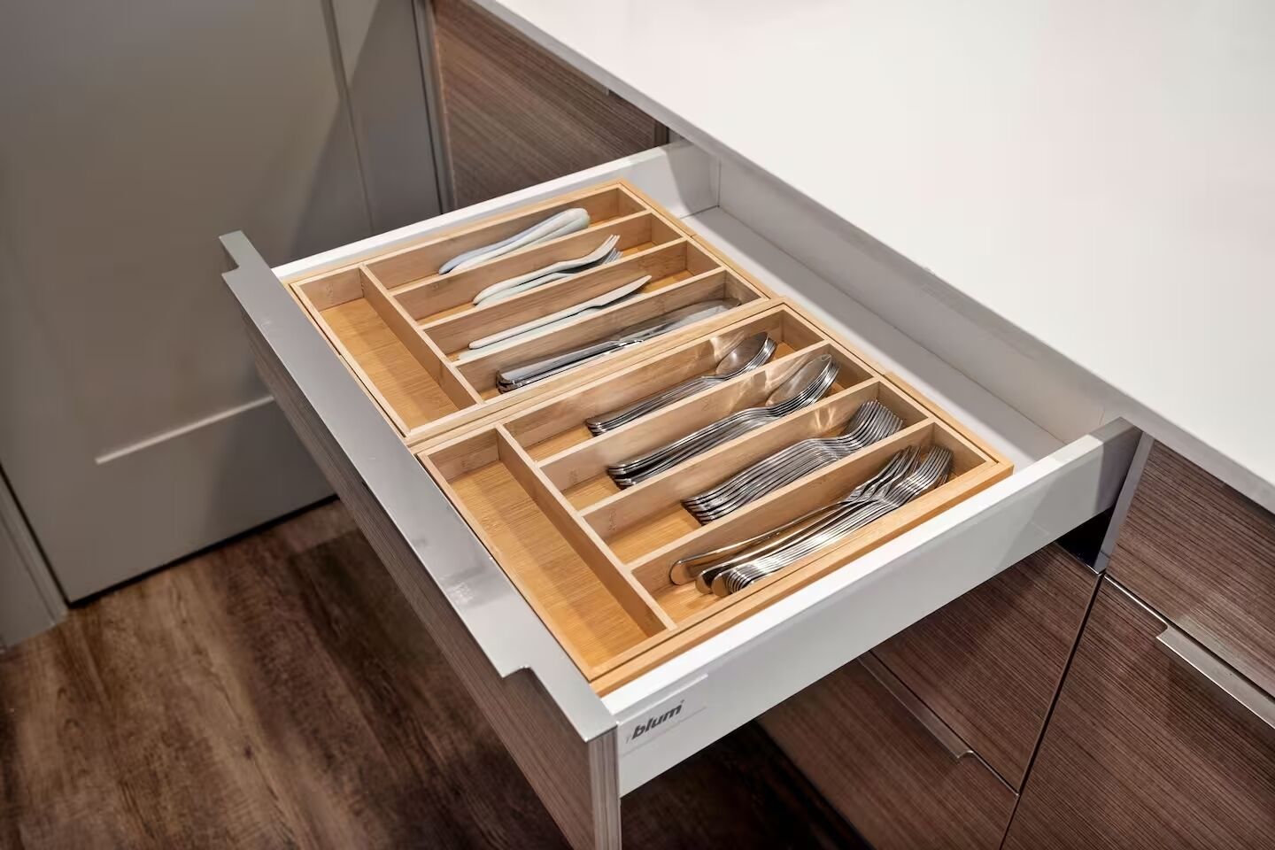Un cassetto della cucina con scomparti multipli, ognuno contenente utensili disposti con ordine.