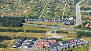 Luftaufnahme einer Küstenwohngegend mit Häusern, Straßen und einem Strand.