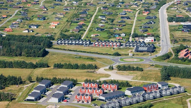 Luftaufnahme einer Küstenwohngegend mit Häusern, Straßen und einem Strand.