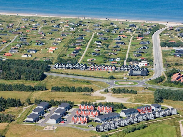 Vue aérienne d’une zone résidentielle côtière, avec des maisons, des routes et une plage.