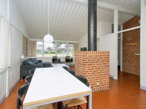 A modern interior with a dining area, a brick fireplace, and a view of the outdoors. - 6 Person Holiday Park Home in Gilleleje (Gilleleje)