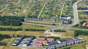 Oversigtsbillede af et kystnære boligområde med huse, veje og en strand.