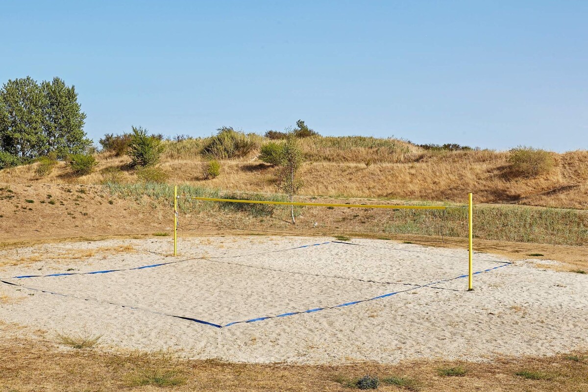 Una cancha de voleibol con una red, rodeada de hierba seca y vegetación escasa.