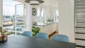 A modern kitchen with white cabinets, a large window, and a view of a marina.