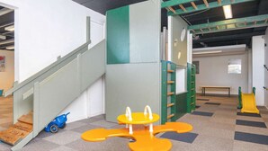 Zona de juegos infantiles con un sube y baja, una pared de escalar y un tobogán.