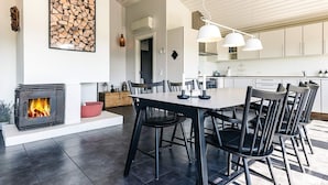 Una cocina moderna con armarios blancos, estufa integrada e iluminación colgante.