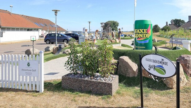 Entrada a un campo de golf con un letrero que dice 'Adventure Golf' y un gran anuncio de 'Faxen Konni'.