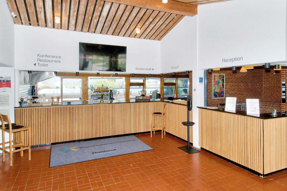 A reception area with a wooden counter, a reception desk, and directional signs for conference, restaurant, and toilet.