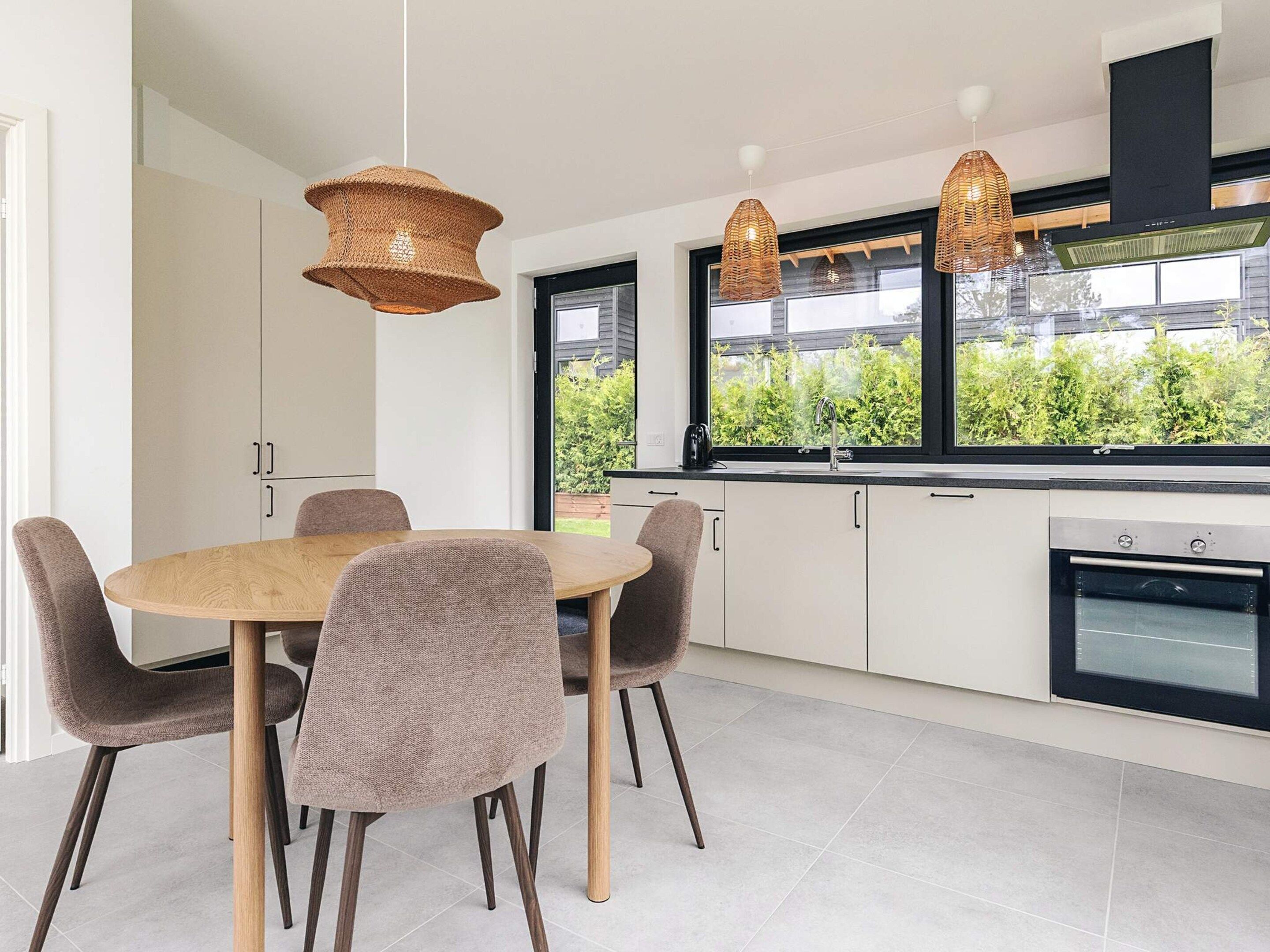A modern kitchen with a dining table, chairs, and pendant lights.