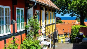 En traditionell byggnad med en röd och gul fasad, vita fönsterramar och ett tak täckt med takpannor.