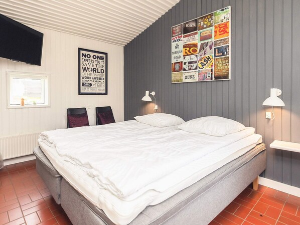 A neatly made bed with white linens in a room with a grey wall and a poster collage. - Holiday Home- Free Water Park Access (Middelfart)