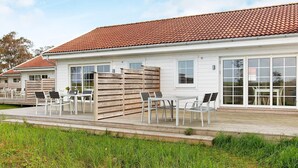 A white building with a red-tiled roof, large windows, and outdoor seating with chairs and tables. - 4 Star Holiday Home in Laeso (Læsø)