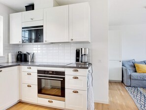 A modern kitchen with white cabinetry, a built-in oven, a microwave, and a coffee machine. - 4 Star Holiday Home in Laeso (Læsø)