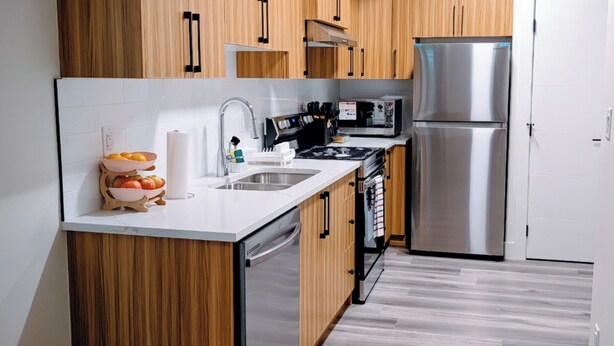 Una cocina moderna con armarios de madera, electrodomésticos de acero inoxidable y encimera blanca.