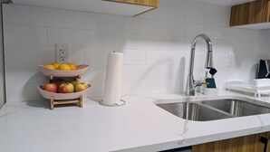 Una cocina con un lavamanos doble, un frutero y un dispensador de toallas de papel.