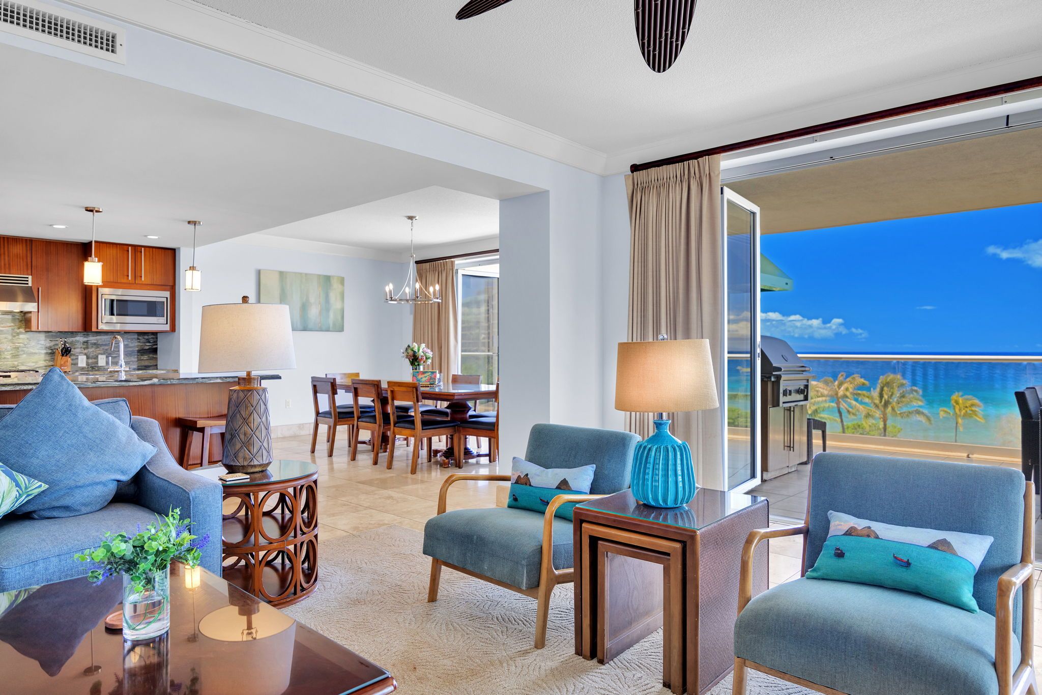 Una habitación de hotel moderna con comedor, cocina y balcón con vista al océano.