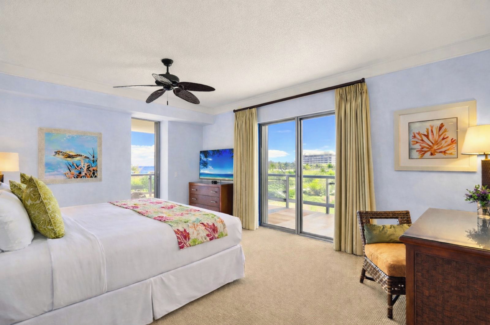A hotel room with a bed, a desk, a chair, a television, a ceiling fan, and a large window with a view.