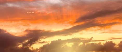 Un coucher de soleil sur une étendue d’eau, avec des nuages dans le ciel.