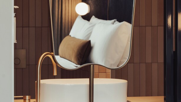 Une salle de bain moderne avec un miroir incurvé, un lavabo et un porte-serviettes.