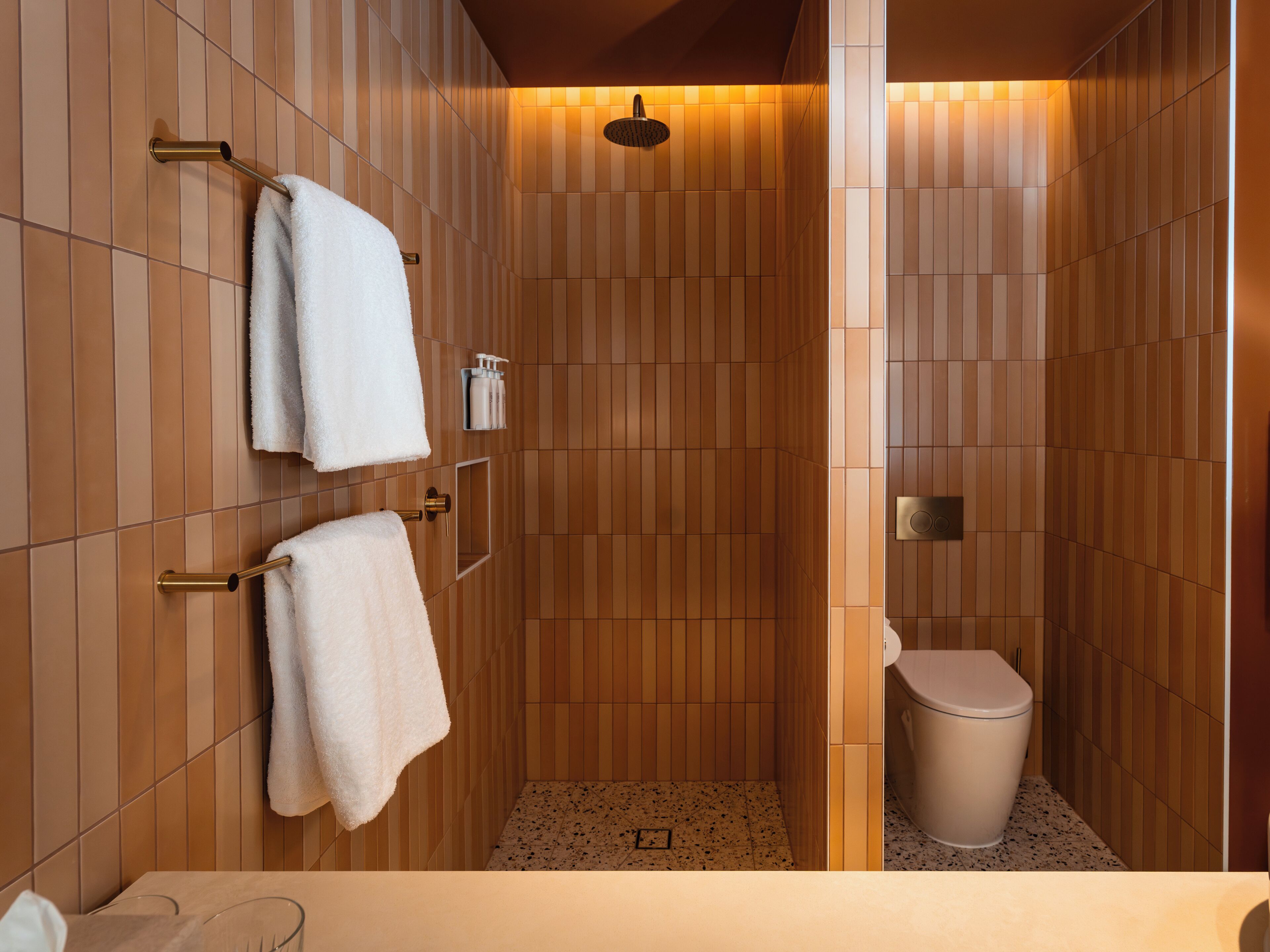 A modern bathroom with wooden paneling, a shower, and a toilet.
