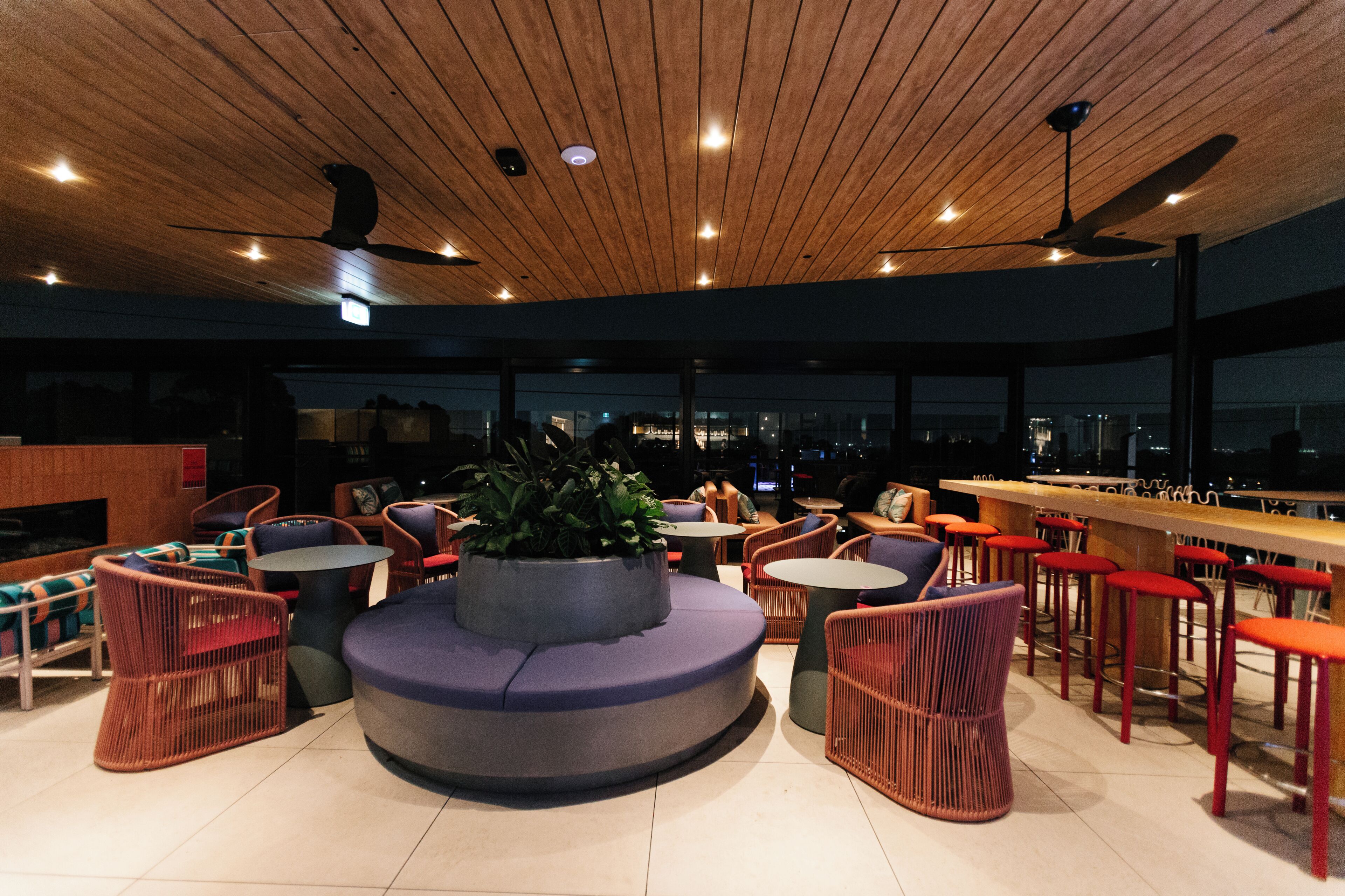 Zona de bar moderna con asientos, una planta central y vistas a la ciudad.