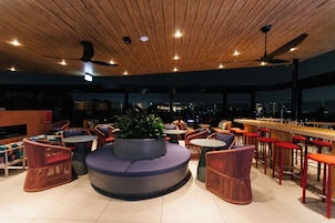 Zona de bar moderna con asientos, una planta central y vistas a la ciudad.