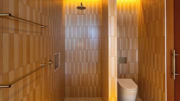 A modern bathroom with a shower, toilet, and towel rack.