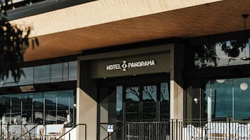 Entrada moderna de un hotel, con un cartel que dice 'HOTEL PANORAMA'.
