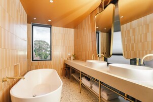 A modern bathroom with a freestanding bathtub, dual sinks, and a large mirror.