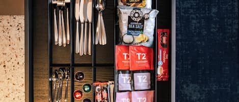 A drawer with neatly organized kitchen utensils, tea bags, and a packet of sea salt.