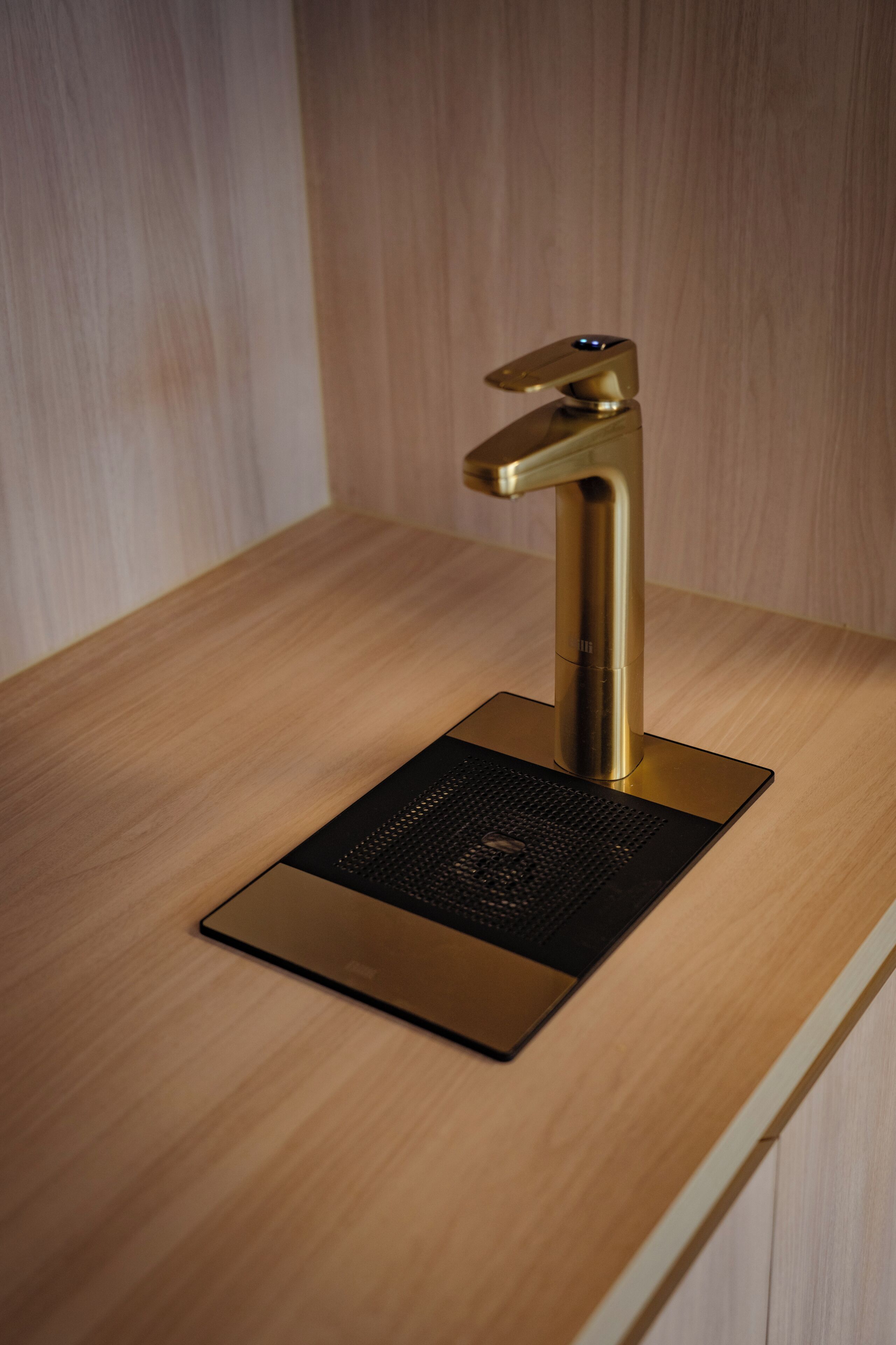 A modern kitchen with a sleek, gold-colored faucet mounted on a wooden countertop.