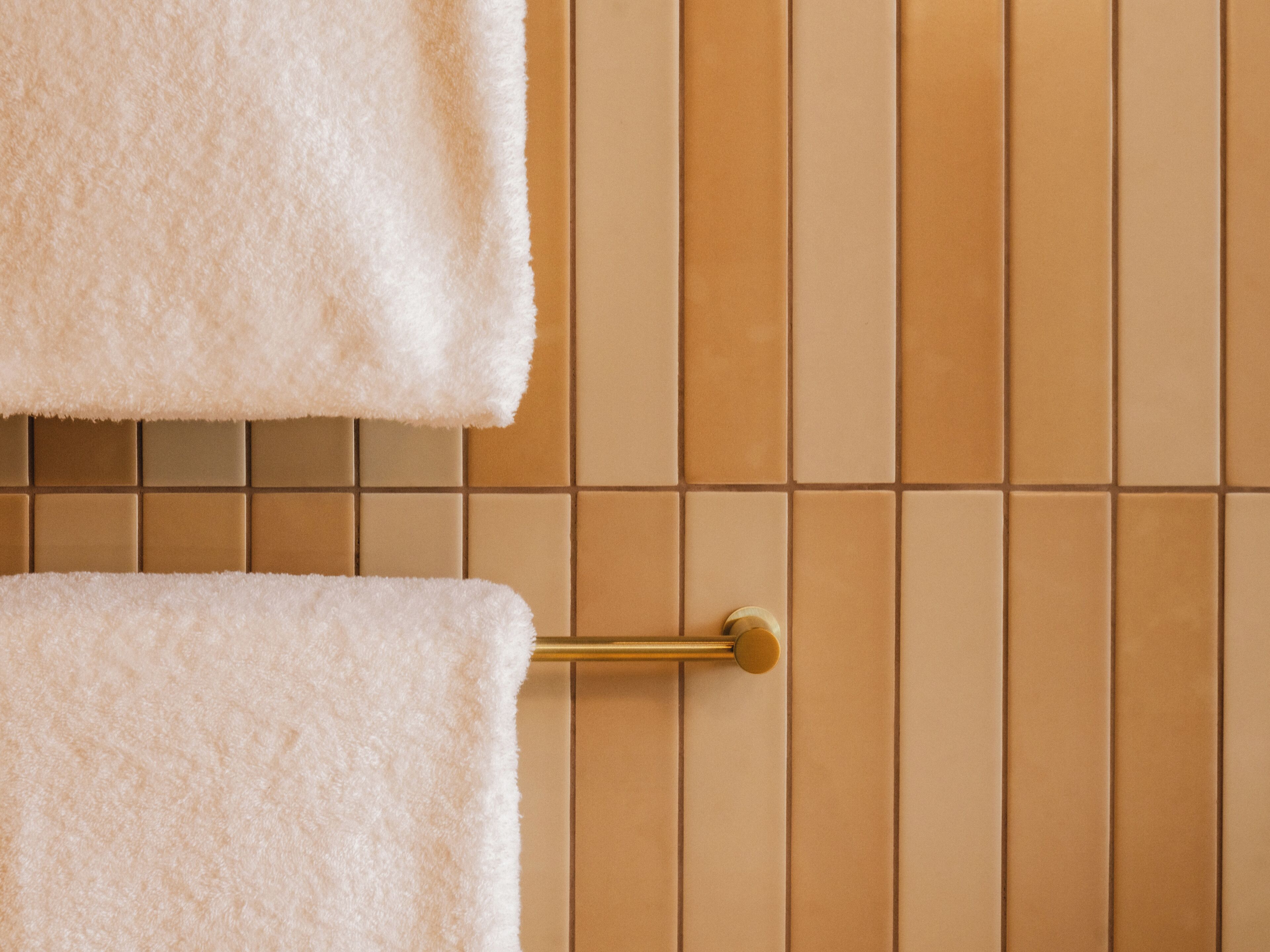 Un baño con toallero y pared con azulejos.