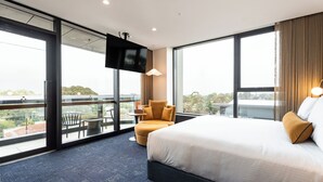 Une chambre d’hôtel avec un grand lit, une télévision, une chaise et un balcon avec vue.
