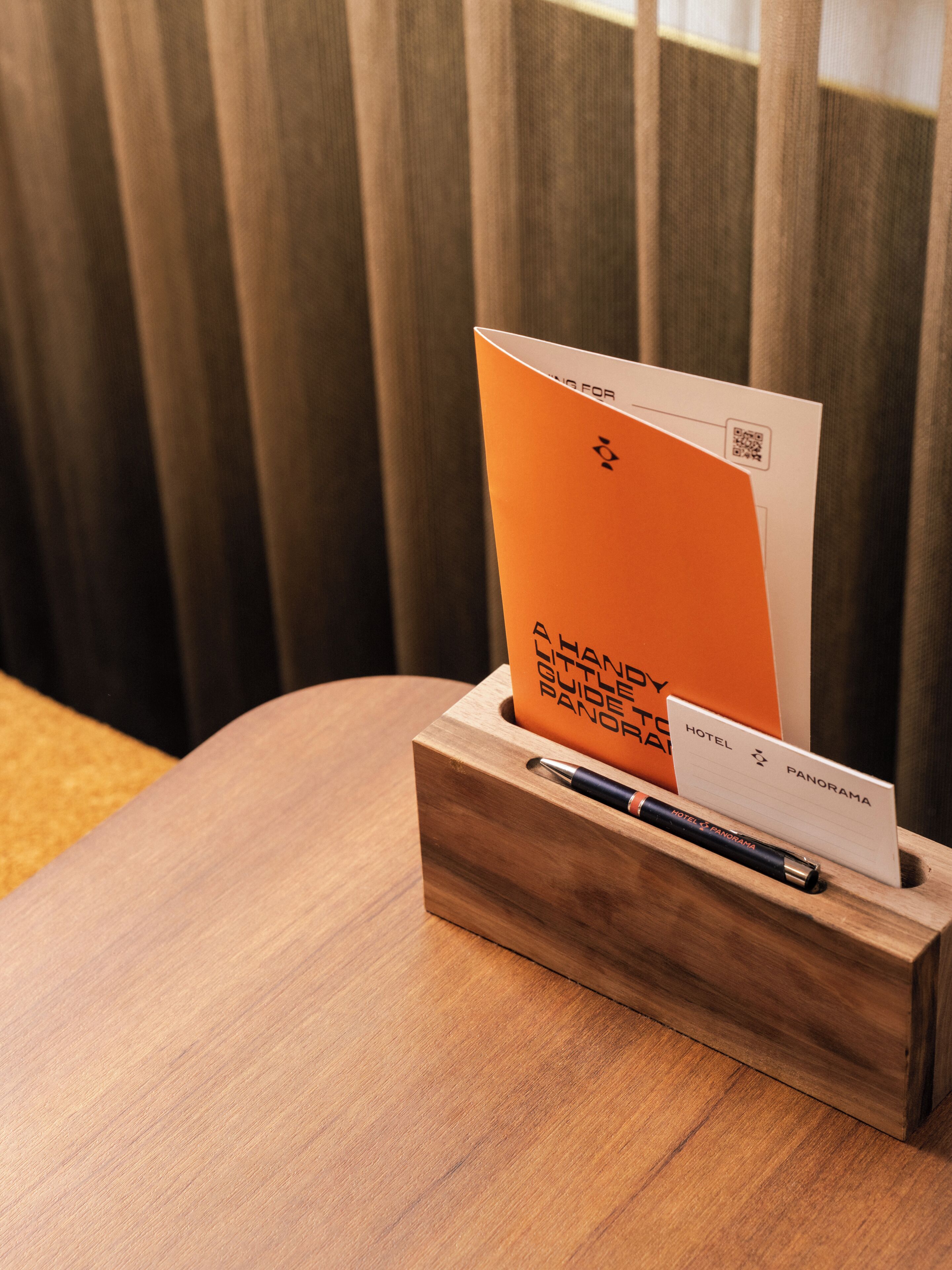 Ein Holztisch mit Stifthalter, der eine Hotelbroschüre und einen Stift enthält.