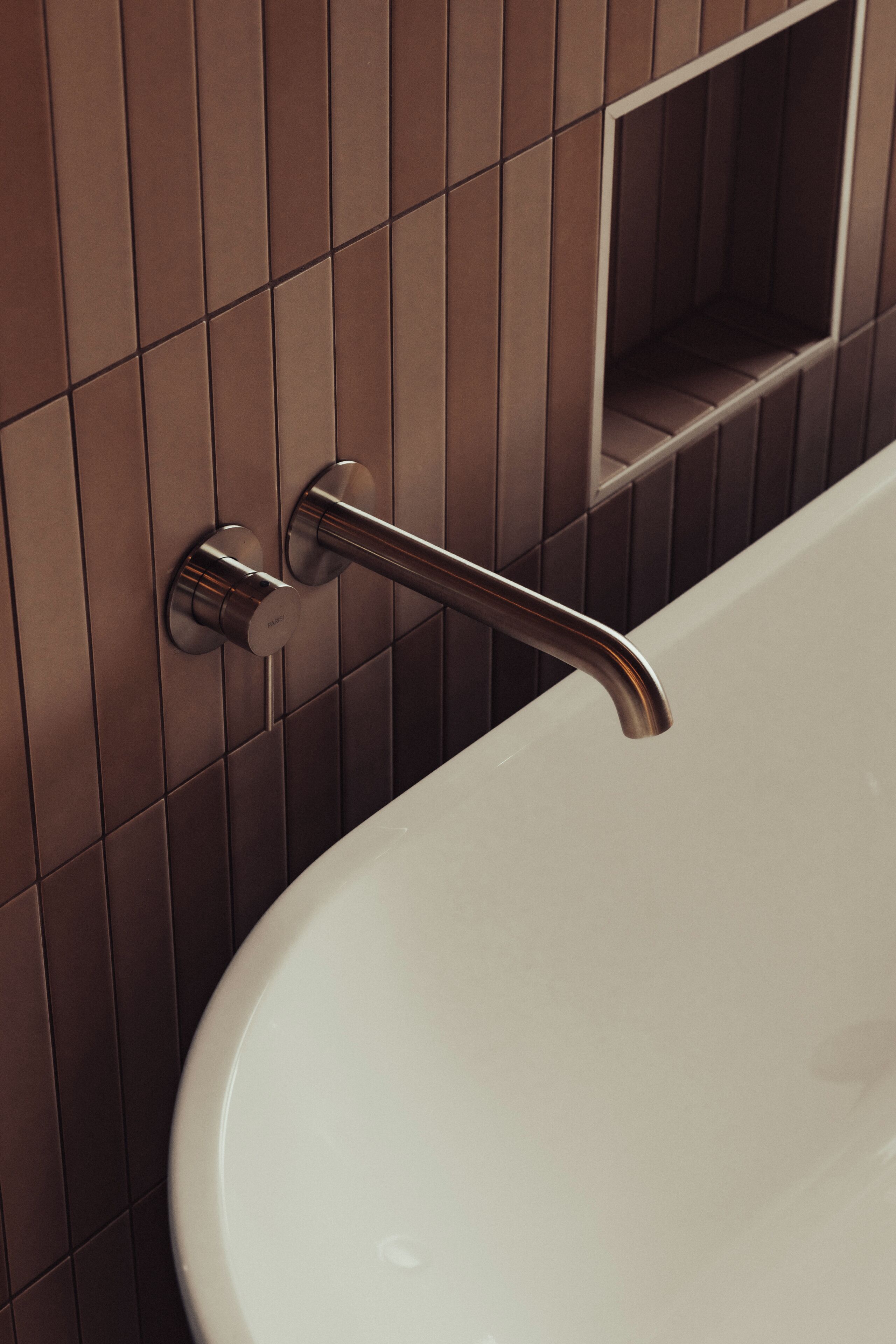 Un baño moderno con una bañera blanca, un toallero en la pared y un estante rectangular.