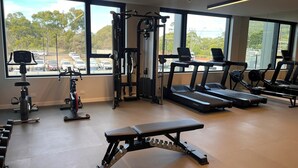 Une salle de sport équipée de tapis de course, d’un banc de développé couché et d’appareils de musculation.