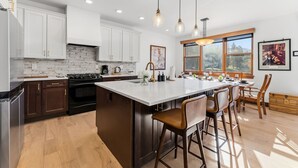 Une cuisine moderne avec des meubles blancs, un grand îlot central et des luminaires suspendus.