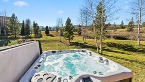 Un bain à remous avec vue sur un paysage verdoyant et des arbres.