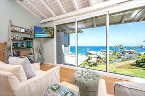 A spacious living room with a large sliding glass door leading to a balcony with a view of the ocean and resort buildings. - Kapalua Bay | Ocean View 2 BR, Sleeps 8 | Car Incl. w/ 6+ Nights | KBV ML-1966 by KBM (Lahaina)