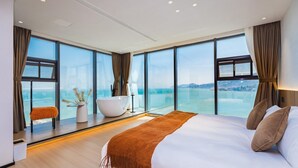 Ein modernes Hotelzimmer mit einem großen Bett, einer Badewanne und Meerblick.