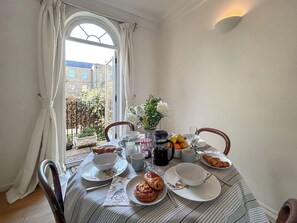 A dining table set with plates, bowls, a vase with flowers, and a croissant. - 2 bedroom accommodation in London (London)